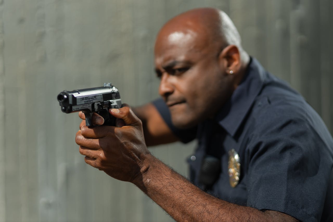 Man in Gray Police Uniform Holding a Gun